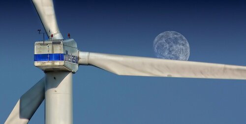 Turbine einer Windkraftanlage, Mond im Hintergrund am blauen Himmel
