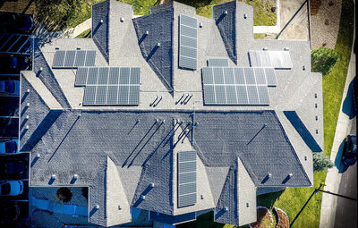 Vogelperspektive: Blick auf ein Hausdach, bestückt mit Solarmodulen