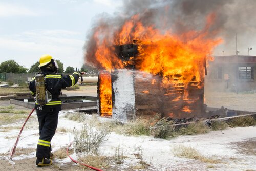 Feuerwehrmann löscht einen brennenden Holzverschlag
