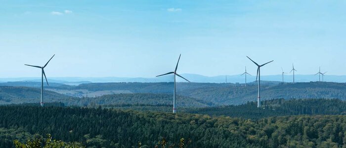Im Bildvordergrund befinden sich die acht Anlagen des Windparks Kreuzstein im Kaufunger Wald, östlich von Kassel. Sie haben je 3 MW Leistung, sind seit 2017 in Betrieb und können 21.000 Haushalte mit einem Verbrauch von 3.000 kWh pro Jahr versorgen.
