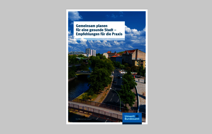 Cover "Gemeinsam planen für eine gesunde Stadt – Empfehlungen für die Praxis": Fluss mit Grünfläche zieht sich durch ein Stadtgebiet, blauer Himmel