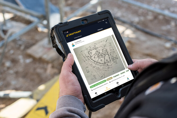 Bauzeichnung auf mobilem digitalem Endgerät, gehalten von einer Person auf einer Baustelle