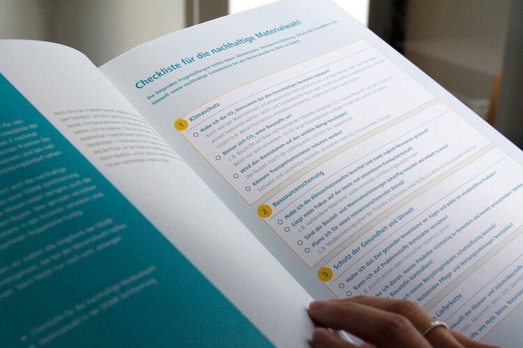 Aufgeschlagener DGNB-Report mit Checkliste zur nachhaltigen Materialwah, eine Hand liegt auf einer Seitel (Quelle: DGNB)