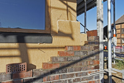 Außendämmung mit Holzfaserdämmstoff-Platten an einem Fachwerkhaus im Umbau mit begonnener Klinkerfassade