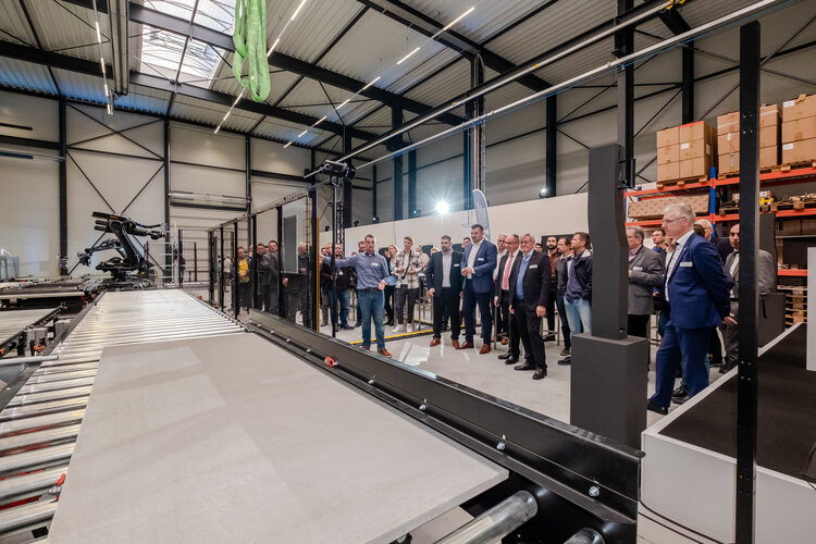 Langer Kipptisch in der Modellfabrik für Carbonbeton in Leipzig; zahlreiche Menschen stehen während der Eröffnung in der Halle