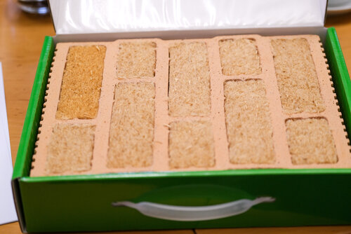 Muster eines klimafreundlich mit Buchenholzfasern gedämmten Ziegels: in einem grünen Koffer befinden sich 5 Ziegelreihen aus Buchenholzfasern