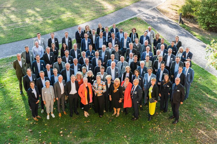 100 Teilnehmende des Ettersburger Gesprächs 2022 in regelmäßigem Abstand zueinander auf einer Rasenfläche stehend, fotografiert aus der Vogelperspektive