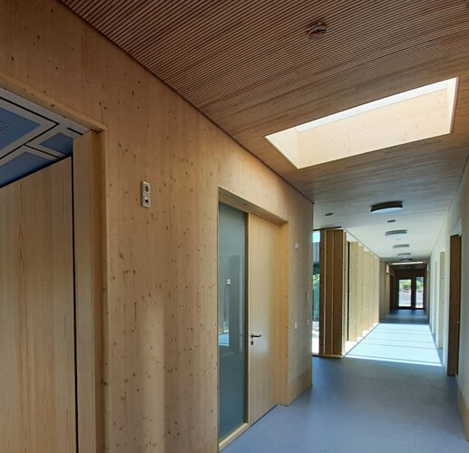 Blick in die umlaufende Veranda mit Holztäfelung und blauem Fußboden verzahnt als Puffer wettergeschützt die Innen- und Außenbereiche.