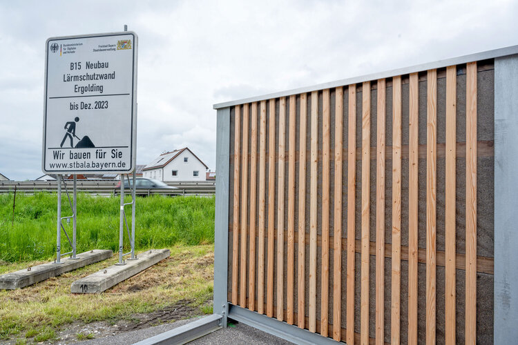 Ein Element der Lärmschutzwand aus Lärchenholz, daneben ein Informationsschild zum Bau "B15 Neubau Lärmschutzwand Egolding"