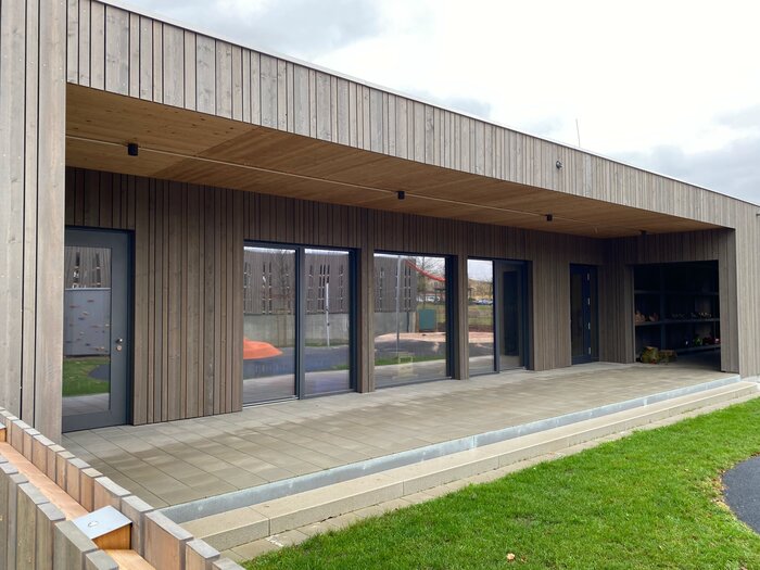  Eingang Gebäude und Veranda, Flachbau aus Holz in grauer Optik