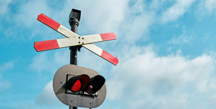 Andreaskreuz mit rotem Signal vor blauem Himmel