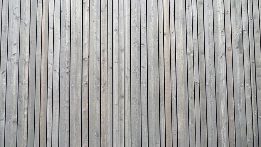 Holzfassade aus längst angebrachten grauen Holzlatten