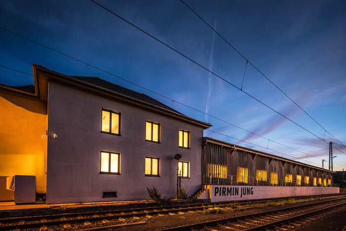 Das umgebaute und sanierte Bahnhofsgebäude des ehemaligen Güterbahnhofs von Remagen beherbergt in seiner knapp 50 m langen und 10 m breiten Halle nun das Ingenieurbüro Pirmin Jung. Es bietet nicht nur viel Platz im Innern, sondern ist auch zentral gelegen.