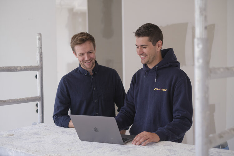 Jonas Stamm und Dr.-Ing. Patrick Christ, Inhaber und Geschäftsführer von Crafthunt auf in einer Baustellen-Wohnung an einem Laptop