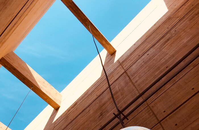 Holzbalkenkonstruktion: Blick nach oben in den blauen Himmel durch Aussparungen in der Konstruktion